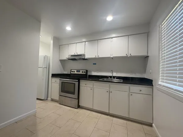 a kitchen with granite countertop white cabinets and stainless steel appliances