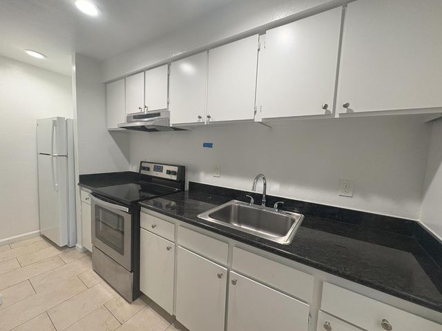 a kitchen with stainless steel appliances granite countertop a sink a stove and a refrigerator