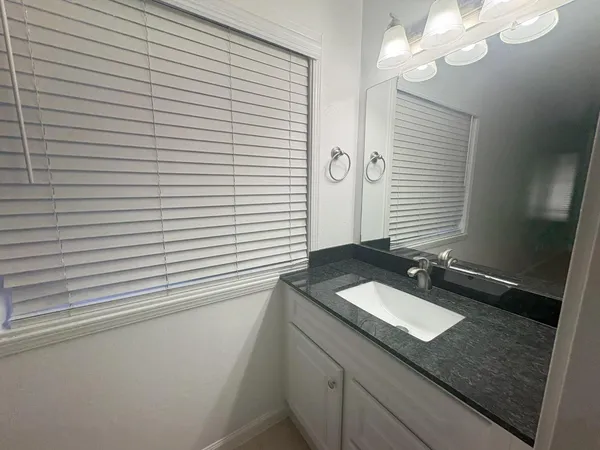 a bathroom with a granite countertop sink and a mirror