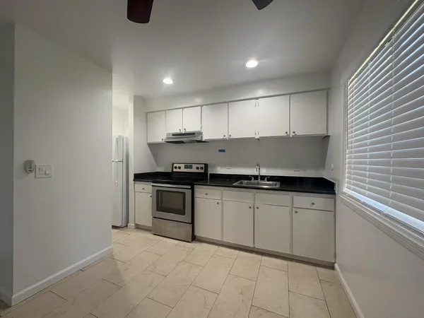 a kitchen with granite countertop a sink a stove and cabinets