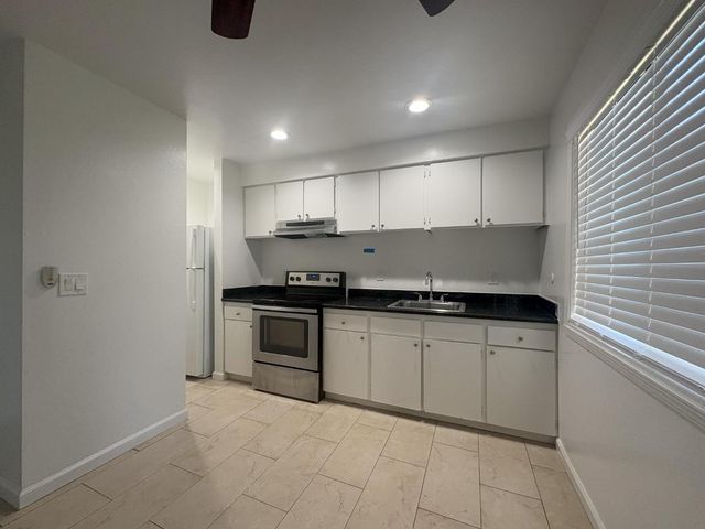 a kitchen with granite countertop a sink a stove and cabinets
