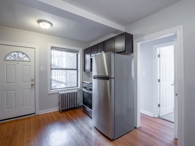 an empty room with wooden floor cabinet and windows