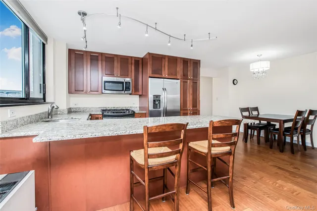 a dining area with stainless steel appliances granite countertop a sink a stove a dining table and chairs with wooden floor