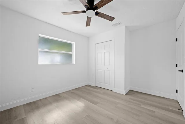 an empty room with ceiling fan and window