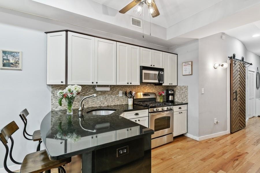 412 Monroe Street, Unit 2 Hoboken, NJ 07030 - Photo 6 of 16 a kitchen with stainless steel appliances a sink a stove cabinets and a dining table
