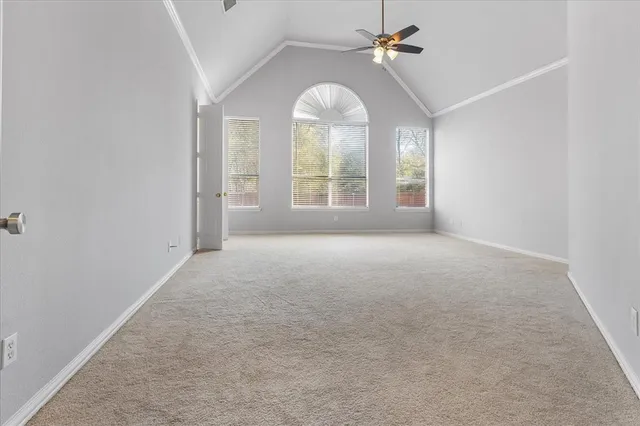 an empty room with chandelier fan and windows