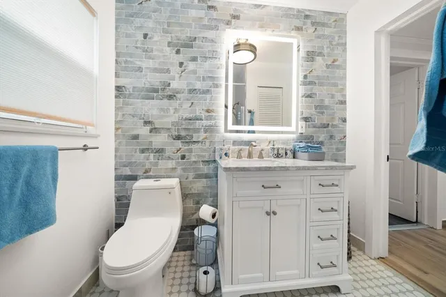 a bathroom with a granite countertop toilet sink and mirror