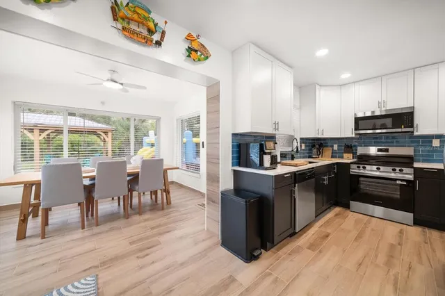 a kitchen with stainless steel appliances kitchen island granite countertop a stove top oven a sink dishwasher a dining table and chairs with wooden floor