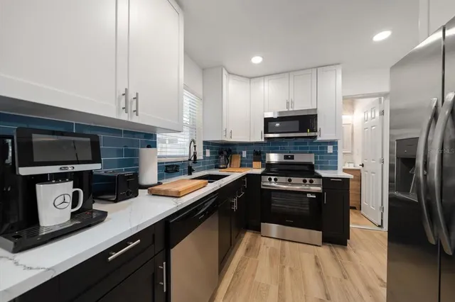 a kitchen with stainless steel appliances granite countertop a refrigerator a stove top oven a sink and dishwasher