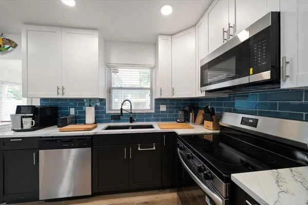 a kitchen with stainless steel appliances a sink dishwasher a stove microwave and cabinets