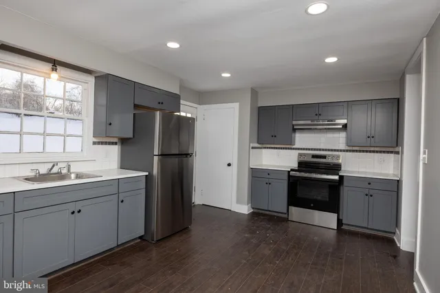 a kitchen with stainless steel appliances granite countertop a refrigerator a sink dishwasher a stove and white cabinets with wooden floor