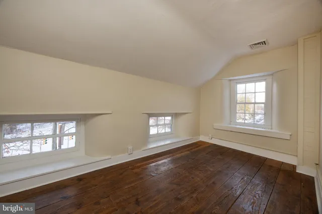a view of an empty room with wooden floor and window