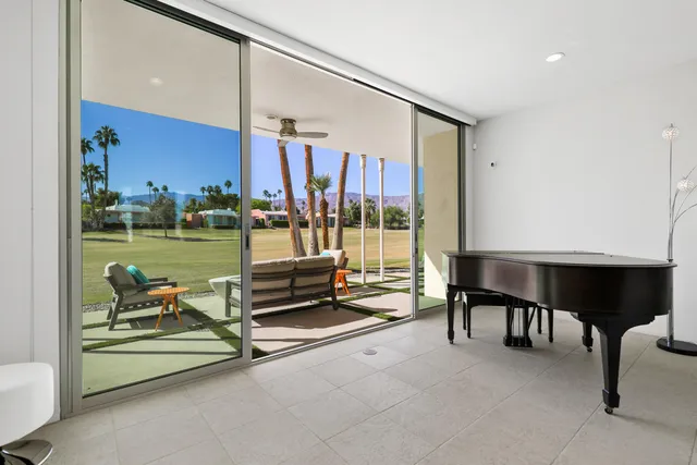a living room with furniture a rug and a floor to ceiling window