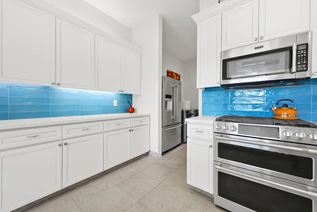 a kitchen with white cabinets and appliances