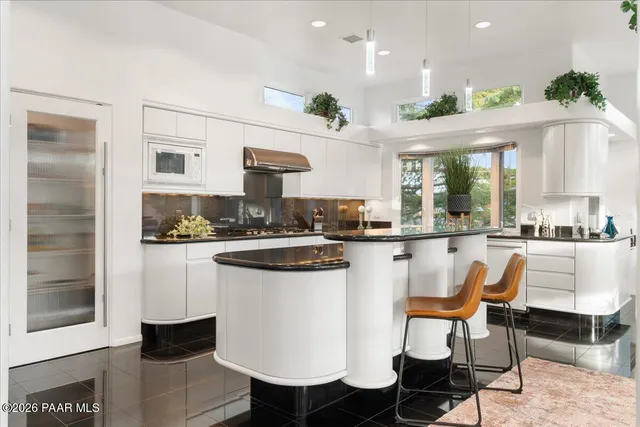a kitchen with stainless steel appliances kitchen island granite countertop a table chairs sink and cabinets