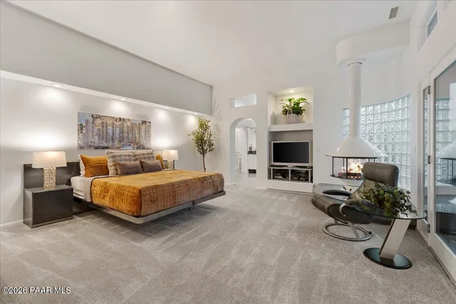 a bedroom with a bed flat screen tv and a fireplace