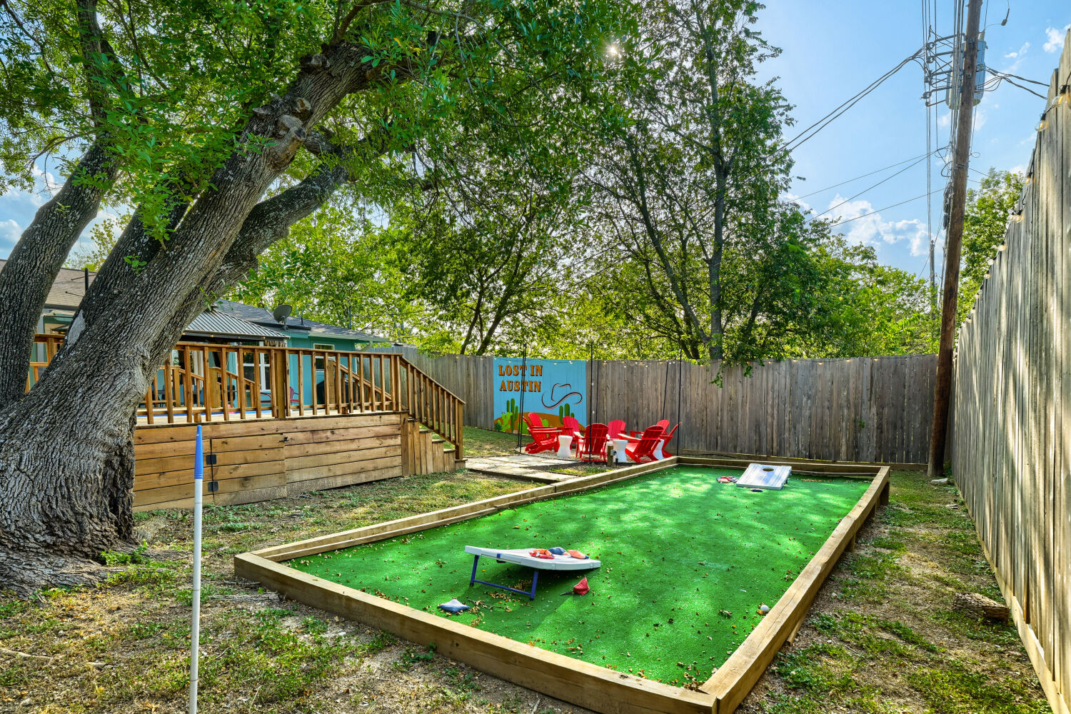 3410 Plantation Road Austin, TX 78745 - Photo 2 of 33 A tiered backyard retreat features a spacious wooden deck and a dedicated green space for games, all enclosed by a natural wood fence.