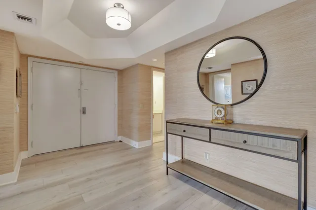 a living room with stainless steel appliances furniture a clock and a view of kitchen