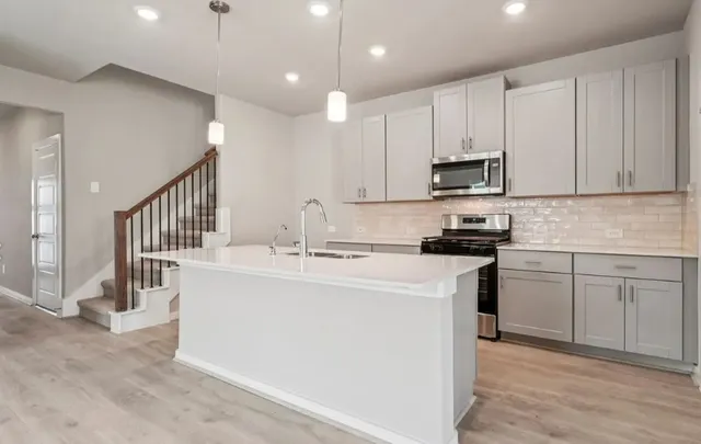 a kitchen with kitchen island sink stove and white cabinets with wooden floor
