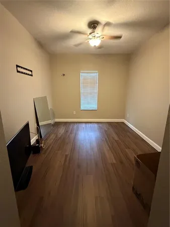 a view of a room with wooden floor and a ceiling fan