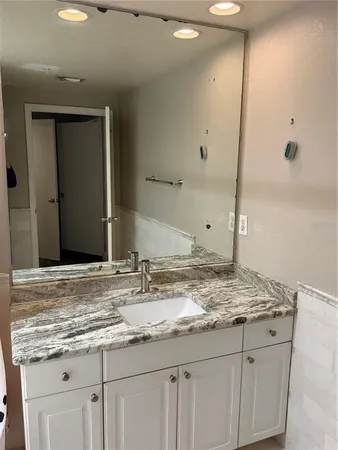 a bathroom with a granite countertop sink and white cabinets