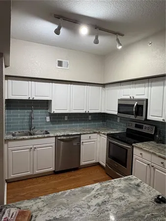 a kitchen with stainless steel appliances granite countertop a sink and stove top oven