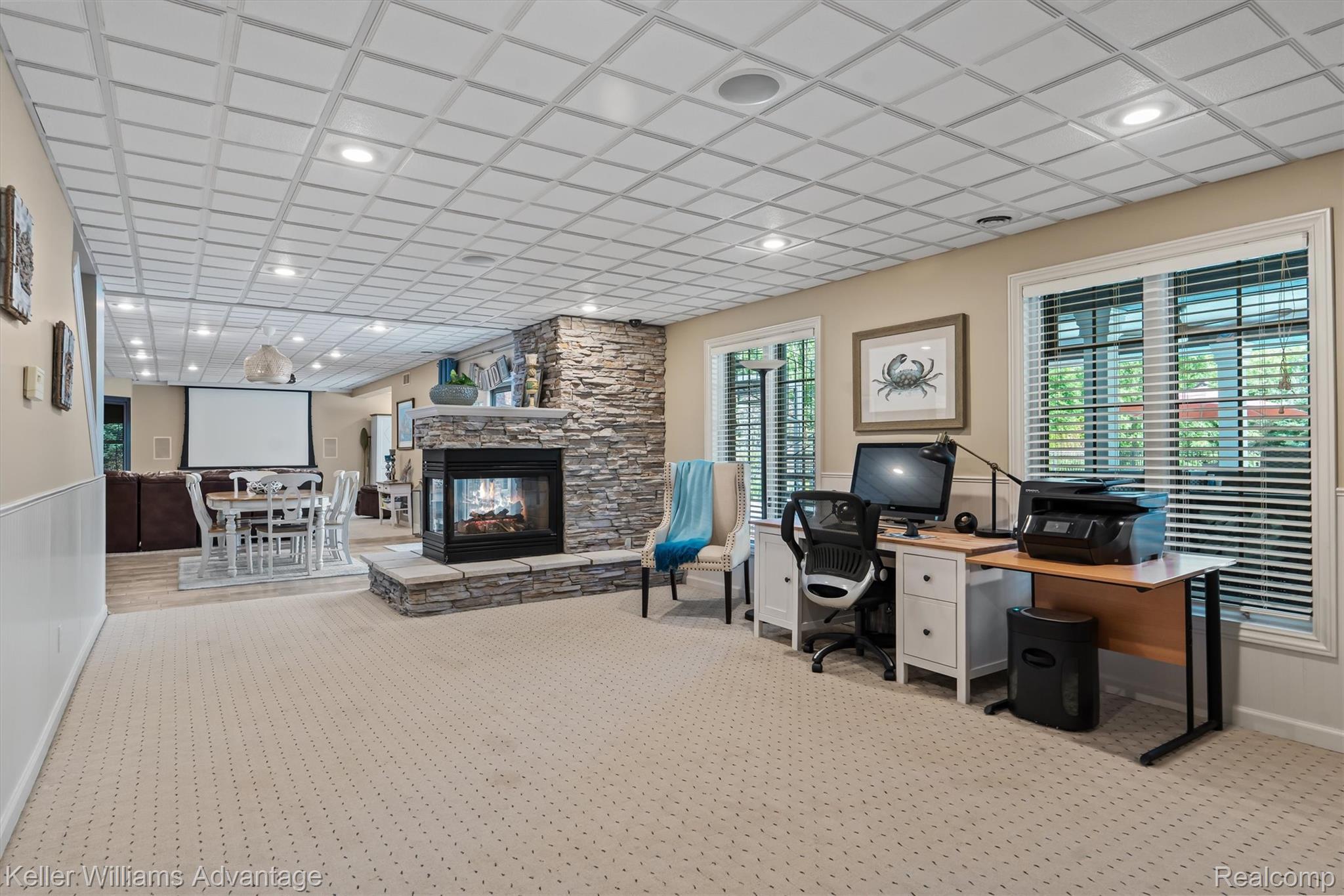 22878 Tree Top Court South Lyon, MI 48178 - Photo 36 of 75 Spacious room featuring a stone-clad fireplace, recessed lighting, two windows with blinds, wainscoting, and a projector screen