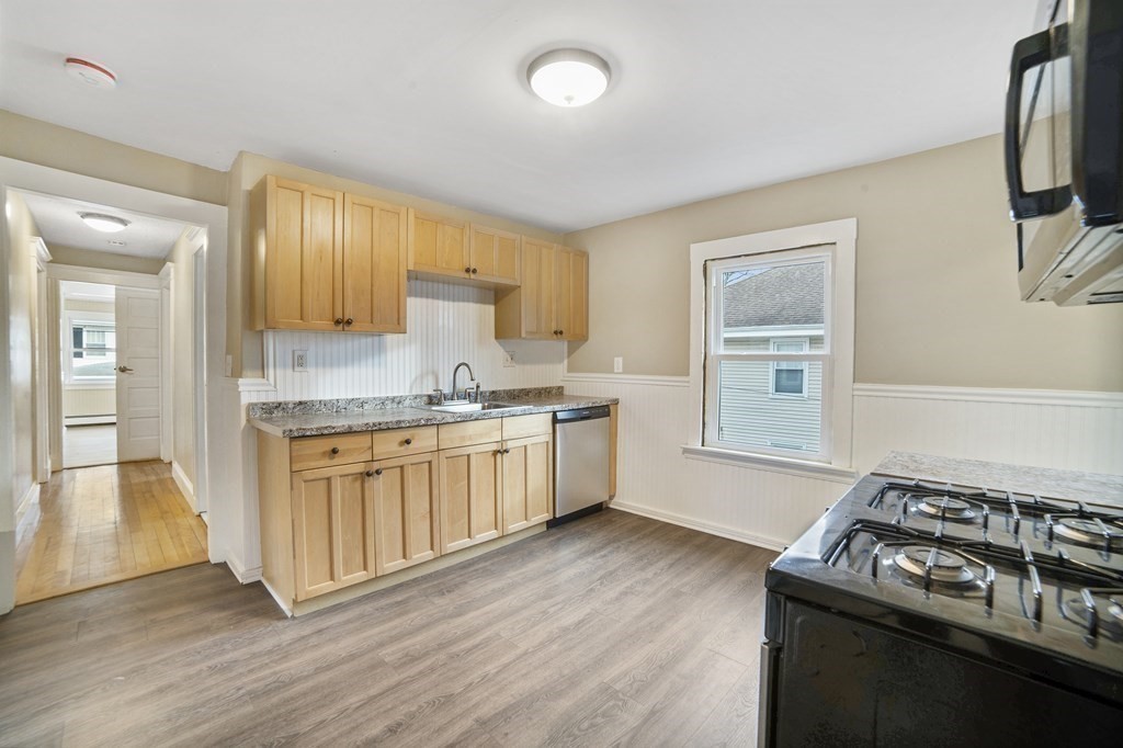 22 Ridgeway Street, Unit 2 Quincy, MA 02170 - Photo 3 of 15 a kitchen with stainless steel appliances granite countertop a stove a sink dishwasher and a refrigerator with wooden floor
