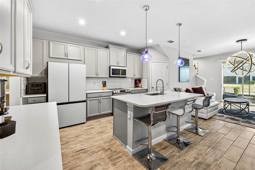 25993 Woven Wicker Bend Lutz, FL 33559 - Photo 25 of 45 a kitchen with kitchen island a stove a sink a microwave a refrigerator a stove and white cabinets with wooden floor