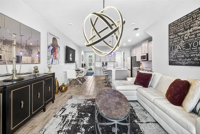 a living room with furniture a large window and stainless steel appliances