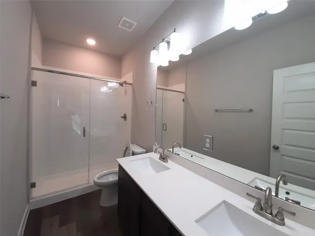 a bathroom with a sink a toilet a shower and a mirror