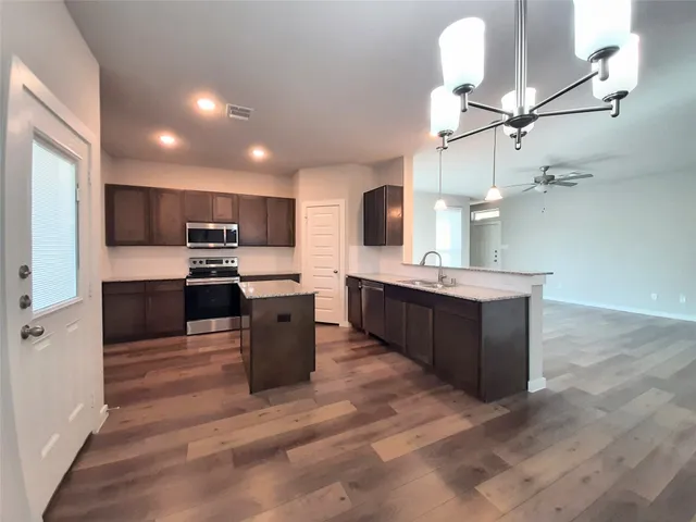 a large kitchen with stainless steel appliances kitchen island granite countertop a sink counter space and cabinets
