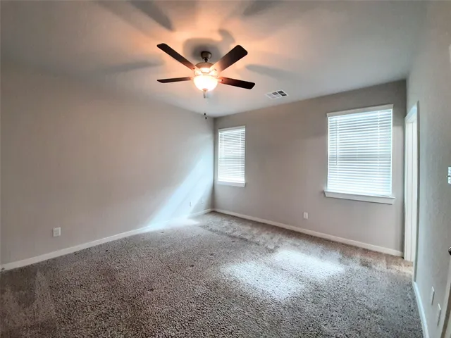 an empty room with windows and fan