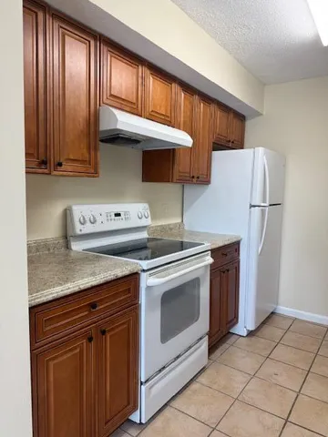 a kitchen with granite countertop wood cabinets stainless steel appliances and a window