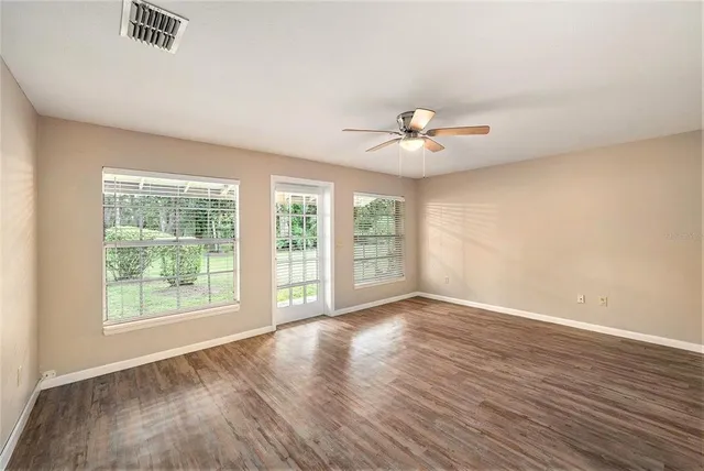 a view of an empty room with a window and wooden floor