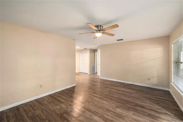 an empty room with wooden floor and windows