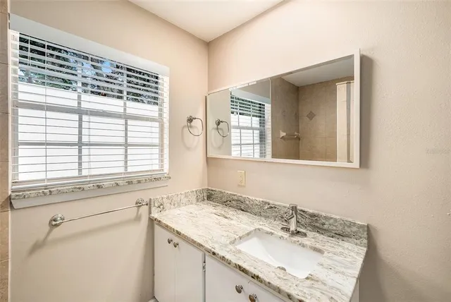 a bathroom with a granite countertop sink and a window