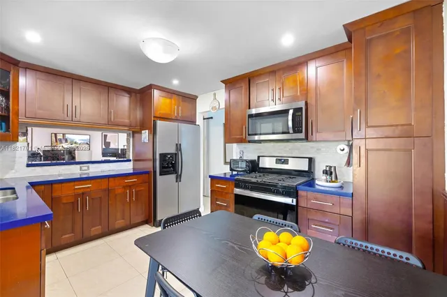 a kitchen with stainless steel appliances granite countertop a refrigerator a stove a sink and a microwave