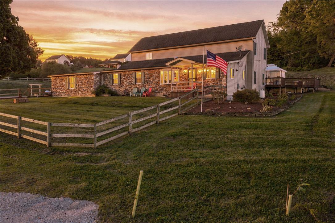 1255 Clearview Road Coplay, PA 18037 - Photo 11 of 54 Golden sunset skies frame a charming home featuring stone accents and rustic wood fencing.
