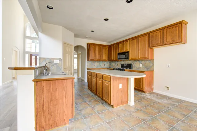 a large kitchen with stainless steel appliances granite countertop a stove a sink dishwasher and a refrigerator