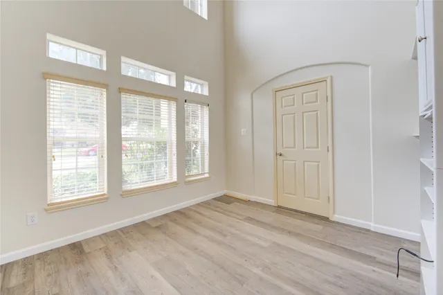 an empty room with wooden floor and windows