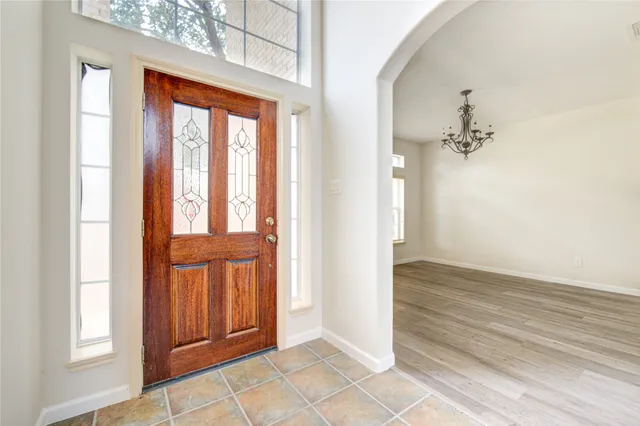 an entryway with wooden floor and a chandelier