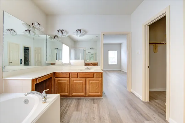 a spacious bathroom with a tub sink and mirror