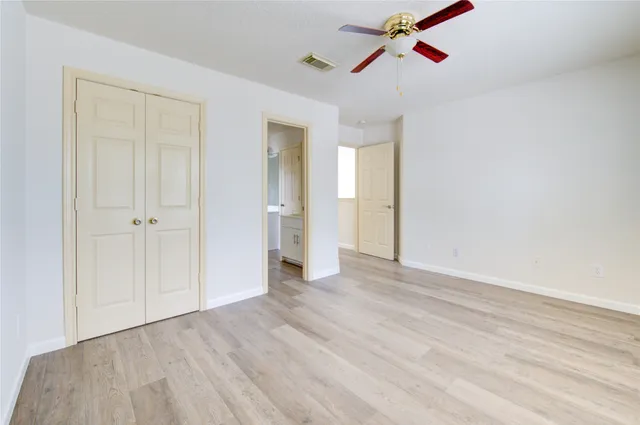 an empty room with wooden floor ceiling fan