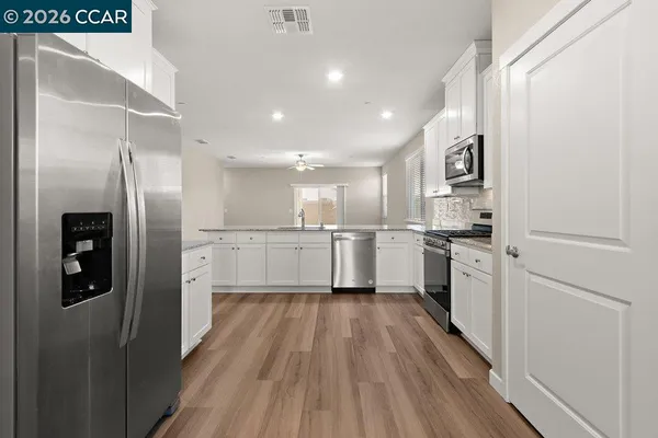 a view of a kitchen with a fridge and wooden floor