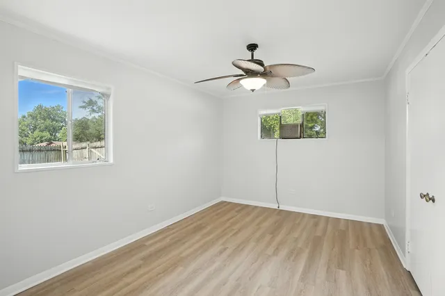 a view of a room with wooden floor chandelier fan and windows