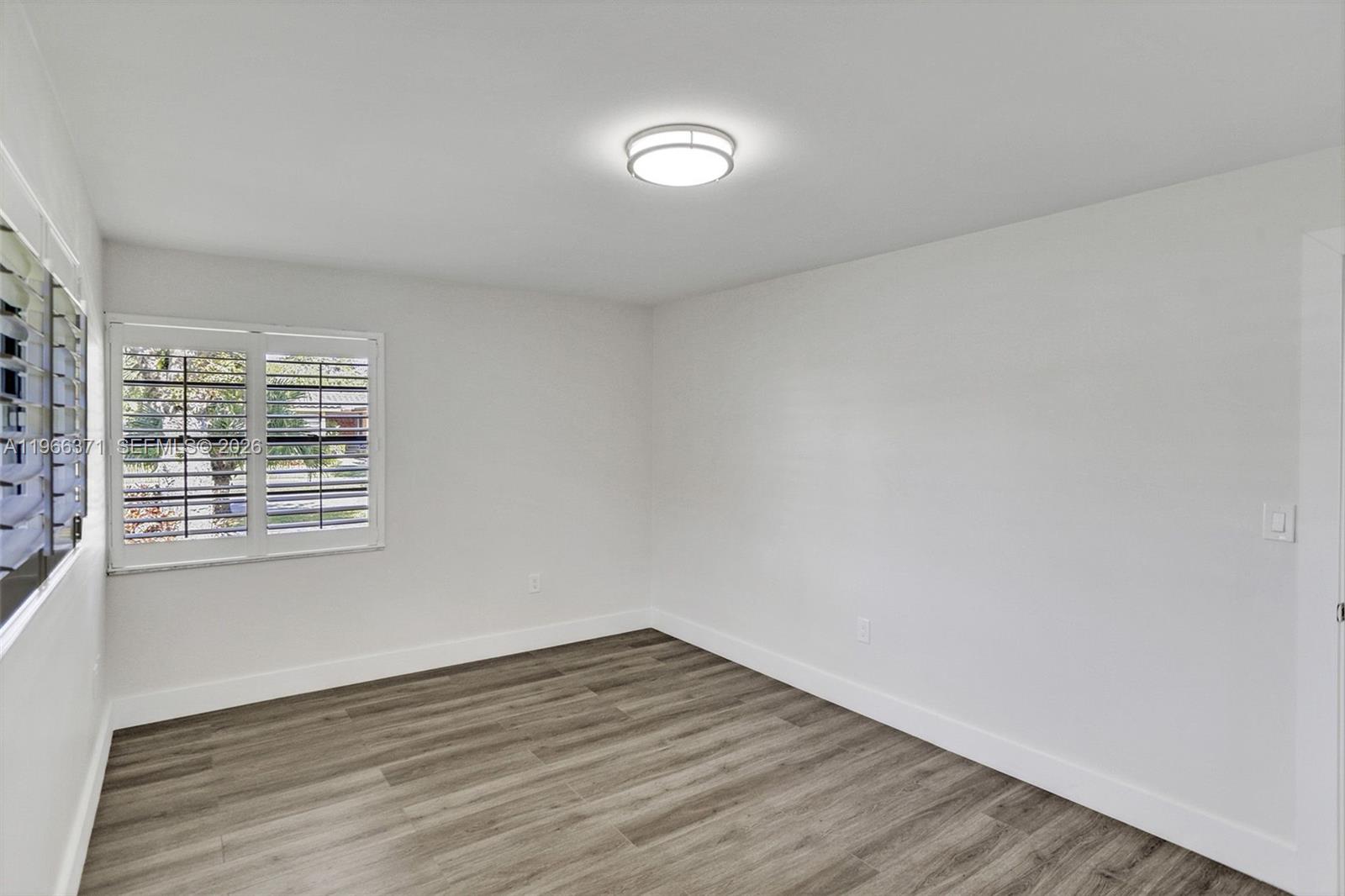 12020 Southwest 93rd Street Miami, FL 33186 - Photo 27 of 42 a view of an empty room with wooden floor and a window