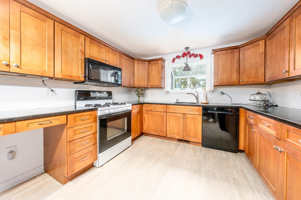 121 S Shellback Way, Unit 121 Mashpee, MA 02649 - Photo 5 of 23 a kitchen with stainless steel appliances granite countertop a stove sink microwave and window