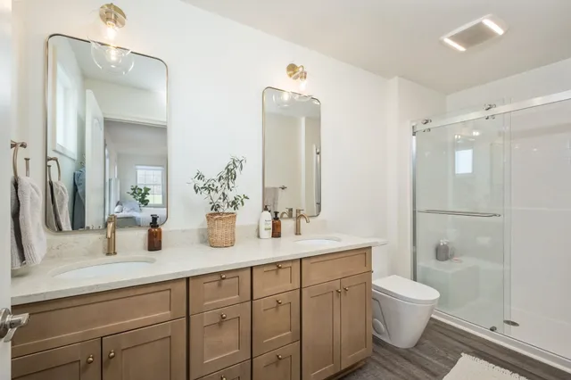 a bathroom with a double vanity sink toilet mirror and shower