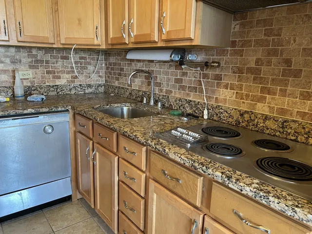 a kitchen with granite countertop a stove sink and cabinets